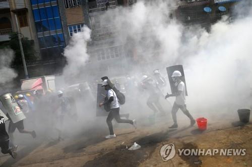 양곤에서 최루탄 속을 뛰어가고 있는 시위대 [AFP=연합뉴스]