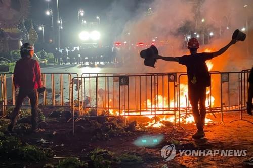 시위대가 불타는 바리케이드 뒤에서 경찰과 대치하고 있다. 2021.3.20 [로이터=연합뉴스]