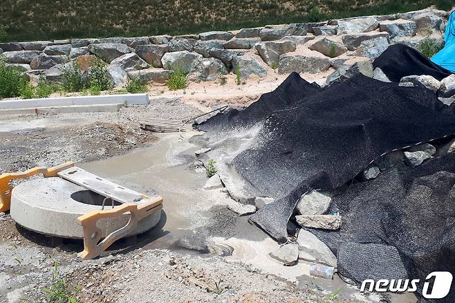 도로 공사현장에 검은 천막 아래 건설폐기물이 방치돼 있고 웅덩이에는 레미콘과 물이 섞인채 고여 있다. 2019.7.2/뉴스1 © News1 김경석 기자