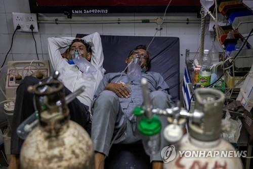 인도 뉴델리 LNJP 병원에서 두 명의 코로나19 환자가 한 침대에서 치료 받고 있다. [이미지출처=연합뉴스]
