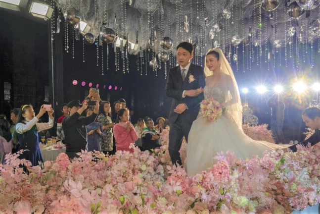 중국 베이징에서 ‘마스크를 쓰지 않는’ 결혼식이 열려 결혼 서약을 한 부부가 하객의 축하를 받으며 걸어 나가고 있다. 베이징 AP 연합뉴스
