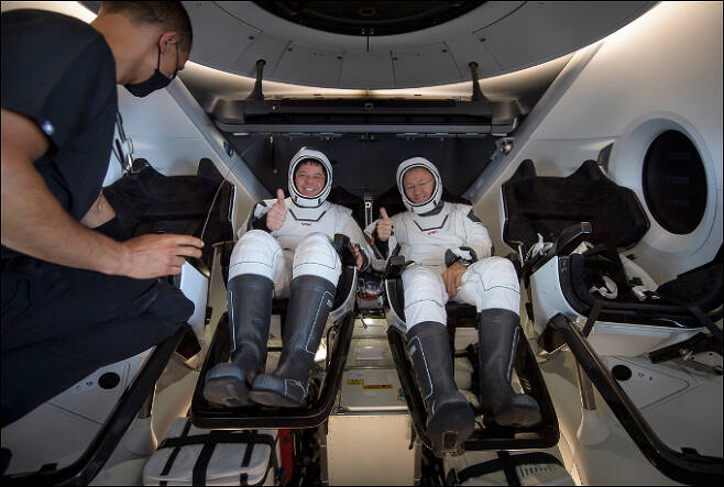 스페이스X의 유인우주선 '크루드래곤'의 해치가 열리자 NASA 우주인 더글러스 헐리와 로버트 벤켄가 미소를 짓고 있는 모습이다. NASA 제공