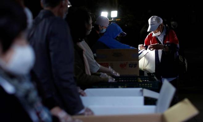 2020년 5월 9일 일본 도쿄에서 COVID-19 확산이 계속되고 있는 가운데 한 노인이 식량지원을 받고 있다. /사진=로이터