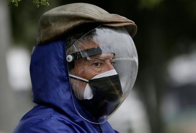 남미 에콰도르 수도 키토의 한 시민이 6일 코로나19 감염을 막기 위해 마스크에 더해 얼굴을 완전히 가리는 플라스틱 보호장비를 착용하고 거리를 걸어가고 있다. 키토=AP 연합뉴스