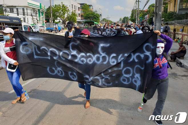 미얀마 양곤 시위대들이 '우리는 민주주의를 원한다'라고 적힌 플랜카드를 들고 시내를 걷고 있다. © AFP=뉴스1 © News1 원태성 기자