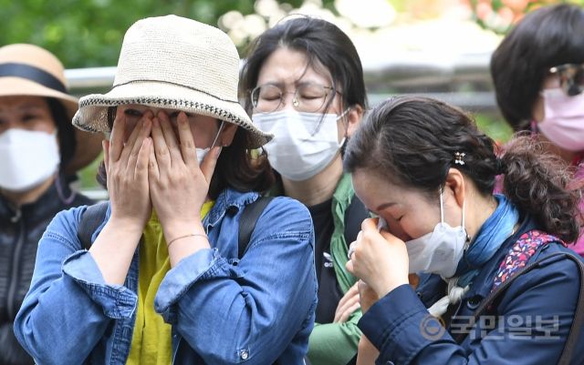 홈플러스 여성노동자들이 13일 서울 종로구 MBK파트너스 본사 앞에서 집단삭발 기자회견을 진행하고 있는 가운데 길 건너의 동료들이 눈물을 닦고 있다.