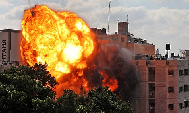13일(현지시간) 이스라엘군의 공습을 맞은 팔레스타인 가자지구 한 건물에서 화염이 치솟고 있다. 가자시티=AFP연합뉴스