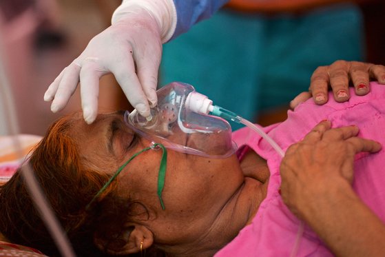 뉴델리의 한 코로나19 환자가 길가에 설치된 병상에서 산소호흡기에 의지해 숨을 쉬고 있다. [AFP=연합뉴스]