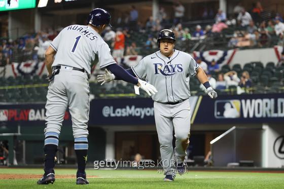 ARLINGTON, TX - OCTOBER 21: Ji-Man Choi #26 of the Tampa Bay Rays is congratulated by Willy Adames #1 after scoring on a sacrifice fly hit by Joey Wendle #18 in the sixth inning during Game 2 of the 2020 World Series between the Los Angeles Dodgers and the Tampa Bay Rays at Globe Life Field on Wednesday, October 21, 2020 in Arlington, Texas. (Photo by Alex Trautwig/MLB Photos via Getty Images)