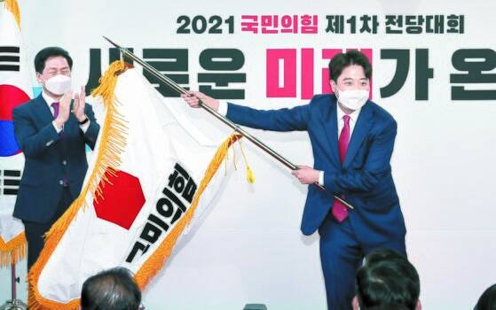 11일 열린 국민의힘 전당대회에서 이준석 대표가 김기현 원내대표로부터 전달받은 당기를 흔들고 있다. 4일간 진행된 경선에서 9만3392표(43.8%)를 얻어 새 당대표로 선출된 그는 “다양한 대선주자와 지지자들이 공존할 수 있는 당을 만들 것”이라고 밝혔다. 오종택 기자