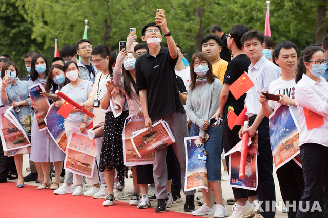 [베이징=신화/뉴시스] 중국 수도 베이징에서 11일 첫 화성 탐사선 톈원의 성공적인 임무 수행을 기념하는 행사가 열린 가운데 시민들이 오성홍기와 화성탐사차 주룽이 전송한 화성표면의 사진을 들고 나와  축하하고 있다. 2021.06.12