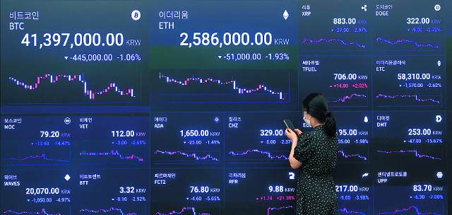 암호화폐 거래소 업비트는 최근 암호화폐 24종의 거래지원 종료(상장 폐지)를 공지했다. 람다, 픽셀, 피카 등은 오는 28일 낮 12시에 최종 상장 폐지된다. 21일 오전 서울 강남구 업비트 라운지 내 코인 시세 전광판 앞에서 한 직원이 서서 휴대전화를 보고 있는 모습. 연합뉴스