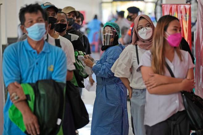2021년 6월 25일 인도네시아 자카르타 외곽 드폭에 마련된 코로나19 백신 접종소에서 보호장비를 착용한 의료진이 중국산 시노백 백신을 접종받기 위해 차례를 기다리는 시민들의 서류를 확인하고 있다. /연합뉴스