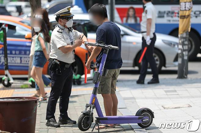 서울 시내에서 경찰이 헬멧을 미착용한 공유형 전동 킥보드를 이용자를 단속하고 있다. 2021.6.13/뉴스1 © News1 성동훈 기자