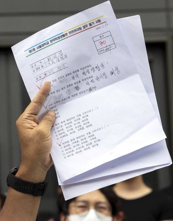 지난 7일 서울대학교 행정관 앞에서 열린 기자회견에서 민주노총 조합원이 청소 노동자가 본 시험지를 들어 보이고 있다. 고인의 시험지는 아니다. 연합뉴스