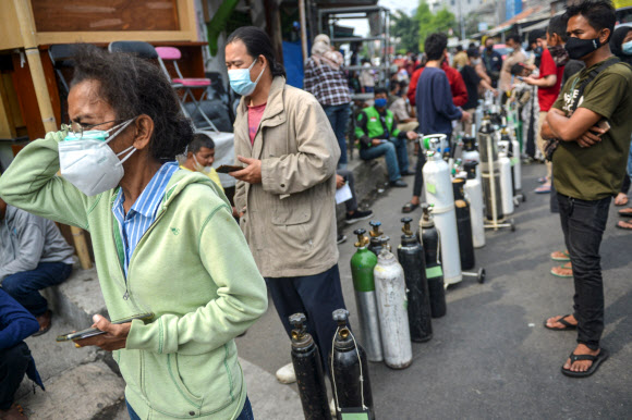 자카르타의 코로나바이러스 질환자 급증 - 2021년 7월 15일 인도네시아 자카르타에서 코로나19 환자가 급증하는 가운데 마스크를 쓴 사람들이 산소통을 들고 서서 무료로 보충하고 있다. 로이터 연합뉴스 2021-07-15