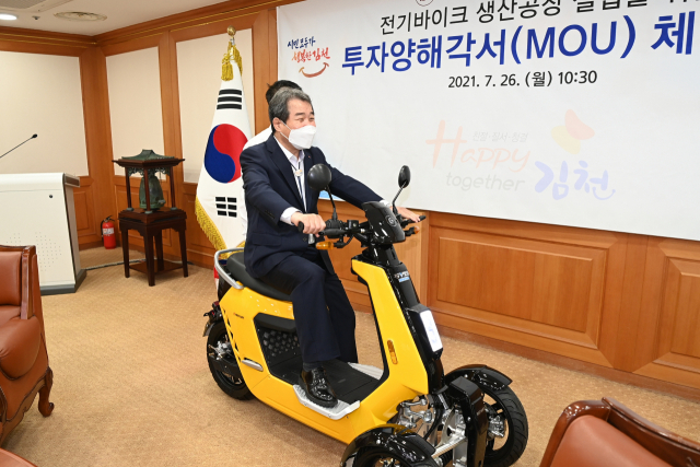김충섭 김천시장이 MOU체결현장에서 이회사가 생산한 전기오토바이를 시승하고 있다.