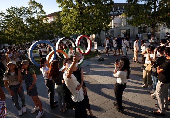 지난달 31일 도쿄 신주쿠에 있는 올림픽주경기장 인근에서 시민들이 올림픽 상징물을 배경으로 사진을 찍고 있다. [로이터=연합뉴스]