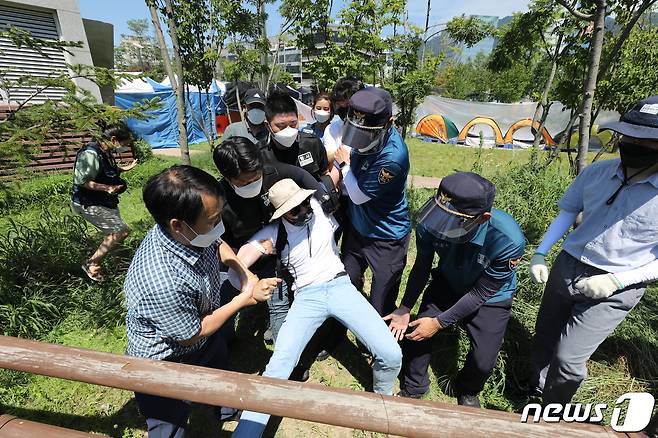 민주노총이 대규모 집회를 예고한 23일 강원 원주시 건강보험공단본부 주변에서 경찰이 집회 장소로 접근하는 노조원을 막아서고 있다. 원주 건보공단 집회는 1인시위만 가능한 상황이다. 강원경찰청은 원주시가 사회적 거리두기 3단계 격상과 함께 집합금지 행정명령을 발표함에 따라 이날 예정된 민주노총 공공운수서비스노조의 ‘비정규직 노동자 직접 고용촉구 집회’를 원천 봉쇄할 계획이다. 2021.7.23/뉴스1 © News1 유승관 기자