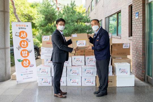 한화토탈 직원(왼쪽)이 지난 9일 고객사 삼동산업을 방문해 김태규 이사에게 서산지역 특산물을 전달하고 있다. <한화토탈 제공>