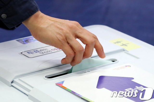 제7회 전국동시지방선거 투표일인 2018년 6월13일 서울 서초구 원명초에 마련된 투표소에서 한 시민이 투표함에 기표용지를 넣고 있다. /뉴스1 © News1