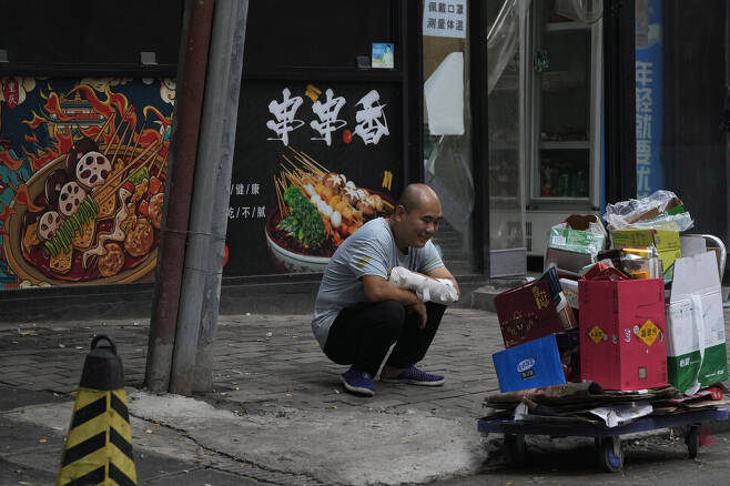 지난 9일 중국 베이징에서 한 남성이 재활용 쓰레기 앞에 앉아 있다. 베이징/AP 연합뉴스