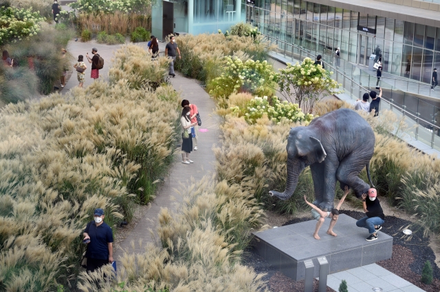 롯데백화점 동탄점 3층과 연결돼 있는 3300㎡의 힐링 공간 '더 테라스'는 국내 최대 규모의 야외 정원이다. 실제 갈대밭이 조성돼 있다. 사진 오른쪽 아래는 코끼리의 무게를 견디는 남자를 묘사한 현대미술가 파비앙 머렐의 작품 ‘펜타튜크’.