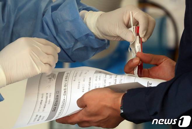 임시선별진료소에서 한 시민이 검체검사키트를 받고 있다.  /뉴스1 © News1 김명섭 기자
