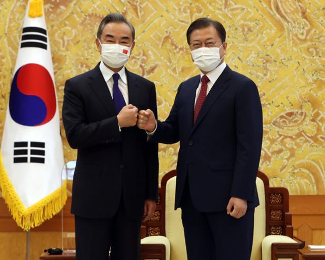 문재인(오른쪽) 대통령이 15일 청와대 본관 접견실에서 왕이 중국 국무위원 겸 외교부장과 주먹인사를 하고 있다. 뉴시스