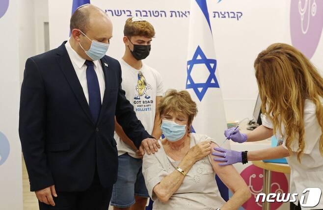 나프탈리 베네트 이스라엘 총리가 2021년 8월 3일(현지시간) 하이파에 마련된 코로나19 백신 접종소에서 3번째 백신을 맞는 어머니를 지켜보고 있다. © AFP=뉴스1 © News1 우동명 기자