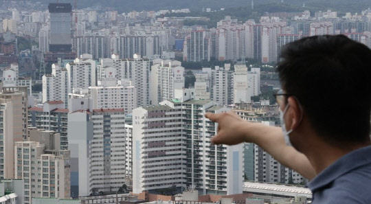 한 시민이 아파트 밀집 지역을 가리키고 있다. <연합뉴스>