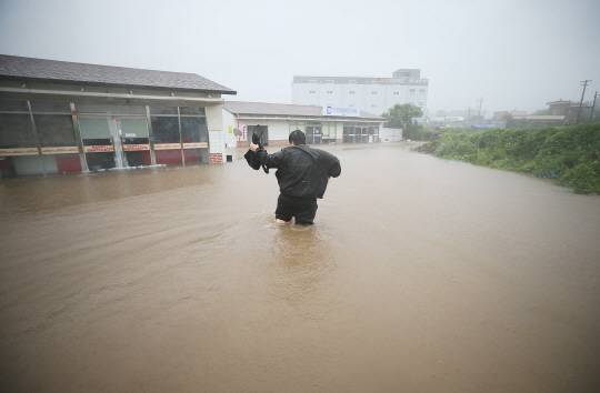 17일 제주 용담2동의 저지대 건물이 태풍 ‘찬투’의 영향으로 침수된 가운데, 한 주민이 무릎까지 찬 빗물을 헤치며 건물을 향해 가고 있다. 연합뉴스