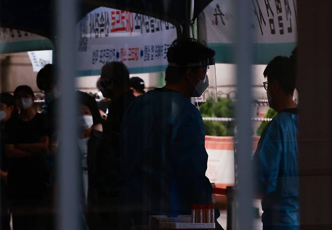 19일 오전 서울역 중구 코로나 임시선별검사소에서 검사소 관계자가 시민들에게 검사 키트를 나눠주고 있다. /연합뉴스