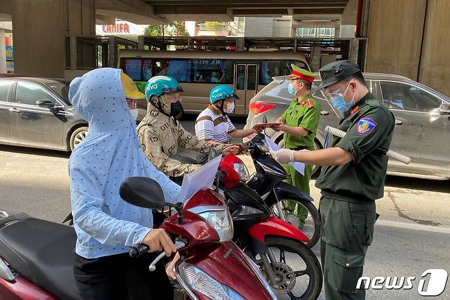 6일(현지시간) 코로나19 확산으로 봉쇄 조치를 연장한 베트남 하노이의 한 검문소에서 경찰이 출근 주민들의 여행 허가서를 조사하고 있다. © 로이터=뉴스1 © News1 우동명 기자