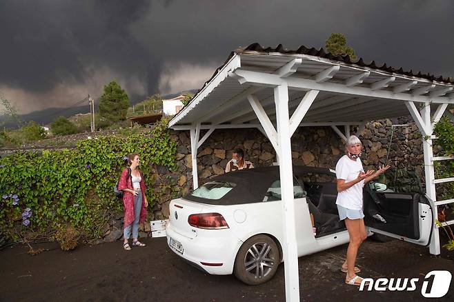 22일(현지시간) 스페인 카나리아제도 라팔마 섬에 있는 쿰브레 비에호 화산이 폭발하자 주민들이 대피를 위해 차량에 가재도구를 싣고 있다. © AFP=뉴스1 © News1 우동명 기자