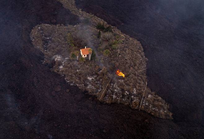 스페인령 카나리아제도 라팔마섬의 화산 폭발에도 피해를 입지 않은 주택. 주변의 검은색 땅은 용암과 화산재가 뒤덮은 것이다. /AP 연합뉴스