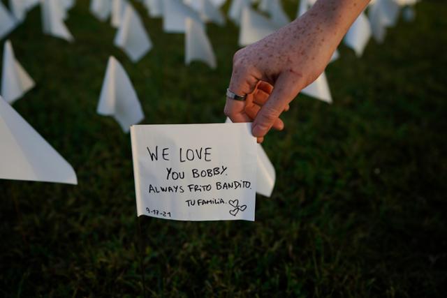17일 미국 워싱턴 내셔널 몰을 찾은 시민이 하얀 깃발에 적힌 코로나19 희생자 추모 메시지를 보고 있다. 워싱턴=AP 연합뉴스