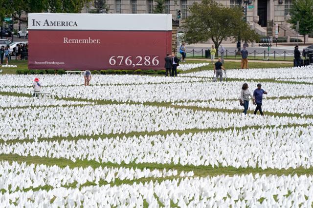 21일 미국 워싱턴 내셔널 몰에 설치된 작품 '미국에서:기억하라' 뒤편으로 코로나19 사망자 수가 표시돼 있다. 워싱턴=AP 연합뉴스