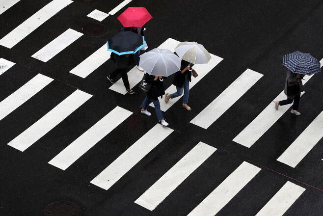 굵은 빗방울을 뿌리는 비구름이 해를 가려 잔뜩 흐린 날씨를 보인 지난 7일 오전 서울 중구 거리에서 우산을 쓴 시민들이 길을 걷고 있다. 연합뉴스