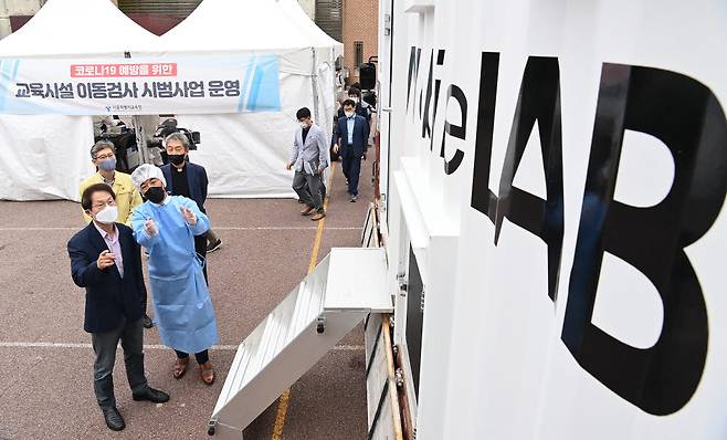 조희연(왼쪽) 서울시교육감이 28일 신속 자가분자진단 유전자증폭(신속 PCR) 검사소가 마련된 서울 종로구 동성고등학교를 방문해 신속 검사 과정을 살펴보고 있다.