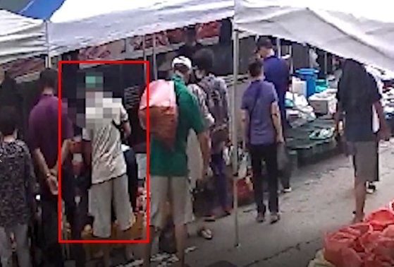 지난달 24일 대전시 유성시장에서 한 남성(붉은색 사각형)이 물건을 사는 여성의 가방에서 지갑을 훔치고 있다. [사진 대전경찰청]