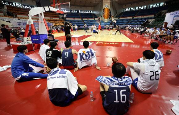 내일을 향해 쏴라 - 2021 프로농구 신인 드래프트에 참가한 후보 선수들이 28일 서울 송파구 잠실학생체육관에서 열린 본 지명행사에 앞서 트라이아웃을 통해 자신들의 기량을 뽐내는 동료의 모습을 플로어에 앉아 바라보고 있다. 올해는 연세대 2학년 재학생인 이원석이 전체 1순위로 서울 삼성에 지명됐다.연합뉴스