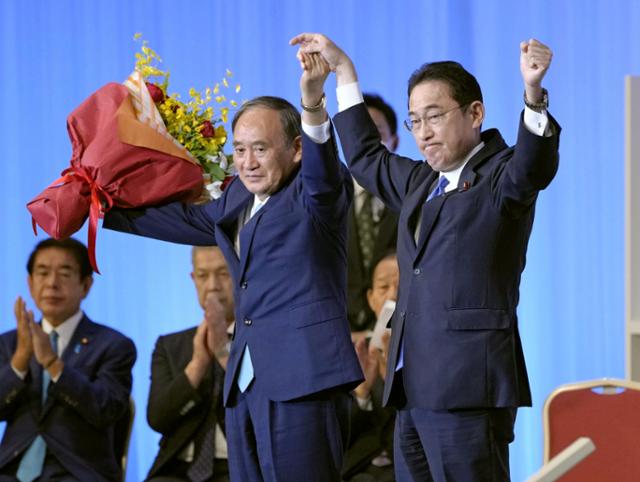 29일 도쿄에서 실시된 자민당 총재 선거에서 당선된 기시다 후미오(오른쪽) 전 정조회장이 스가 요시히데 일본 총리와 함께 양손을 들어 박수에 답하고 있다. 도쿄=교도 로이터 연합뉴스