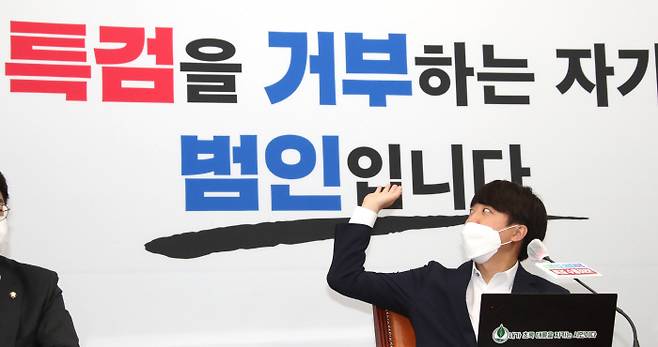 국민의힘 ‘특검 거부=범인’ 이준석 국민의힘 대표가 30일 ‘판교대장동게이트 특검법’ 수용을 더불어민주당에 촉구하는 긴급 기자회견에서 국회 당 대표실 벽면에 적힌 글씨를 가리키고 있다. 국회사진기자단