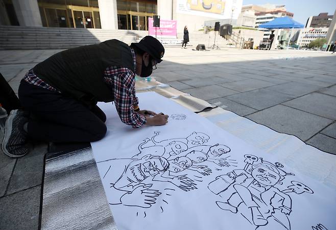 An artist draws a cartoon at a protest held by art groups in front of the Sejong Center for the Performing Arts on Thursday. (Yonhap)