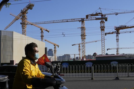 지난 11일 중국 베이징의 한 건설현장 옆을 한 베달업체 직원이 지나가고 있다. [AP=연합뉴스]