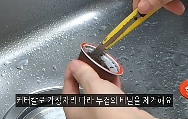커터칼로 캡슐커피 뚜껑을 뜯어 내용물을 빼내는 모습. 유튜브 캡처