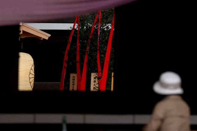 A woman prays in front of a wooden plaque showing the name of Japan's Prime Minister Fumio Kishida seen with a "masakaki" tree that he sent as an offering to the controversial Yasukuni Shrine on the first day of autumn festival in Tokyo on Sunday. (AFP-Yonhap)