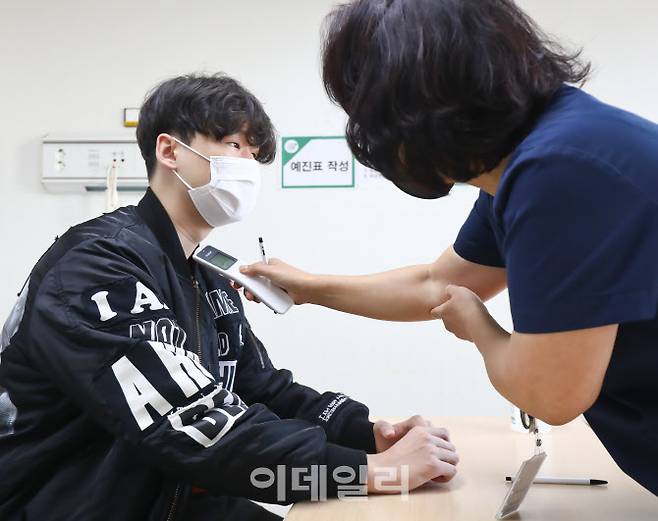 12~17세 소아청소년에 대한 코로나19 백신 접종이 시작된 18일 서울 양천구 홍익병원에서 한 학생이 코로나19 백신접종에 앞서 체온을 확인하고 있다. (사진=공동취재단)