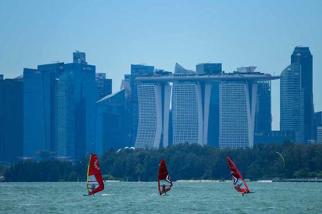 People sail along the East Coast waterway, as the city skyline is seen in the background in Singapore on Oct. 11. (AFP-Yonhap)